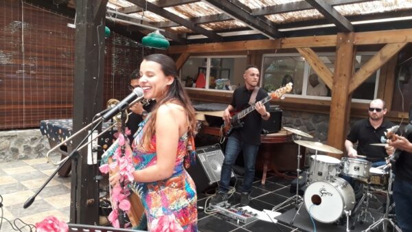 Une chanteuse en robe colorée interprète une chanson au micro sur la scène lors de la remise des prix LanKRéol 2017. À l'arrière-plan, un bassiste et un batteur jouent leurs instruments, entourés d'équipements audio.