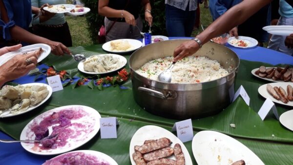 Des convives se servent au buffet lors de la remise des prix LanKRéol 2017. Un grand plat de riz créole et des accompagnements traditionnels sont disposés sur des feuilles de bananier, entourés de plats de viande et de légumes