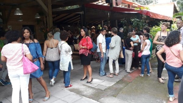 "Les invités arrivent et discutent devant l'entrée de l'espace de la remise des prix LanKRéol 2017. Le groupe est composé de femmes et d'hommes en tenue de cérémonie, échangeant dans une ambiance conviviale.