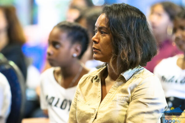 Une femme concentrée écoutant une présentation lors d'une conférence.
