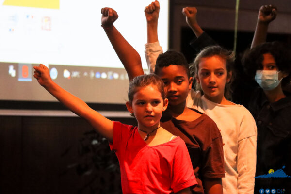 Un groupe d'enfants levant le poing pendant une performance.