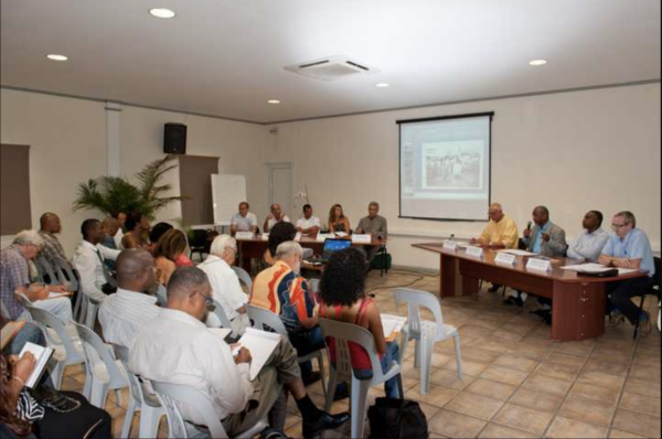 Une table ronde avec plusieurs intervenants et un public attentif lors d'une conférence.