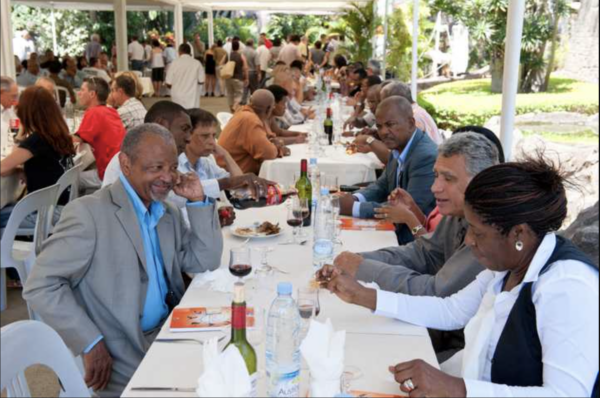 Un déjeuner convivial en extérieur, avec des participants assis à de longues tables, échangeant dans une ambiance détendue