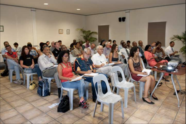 Un public attentif assis sur des chaises en plastique lors d'une conférence.