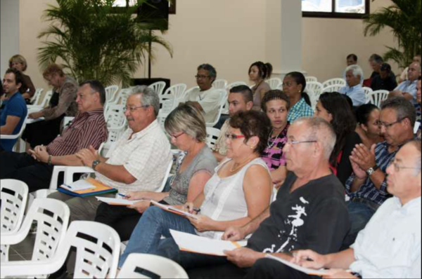 Un groupe de participants assis, prenant des notes et écoutant attentivement lors d'une conférence.