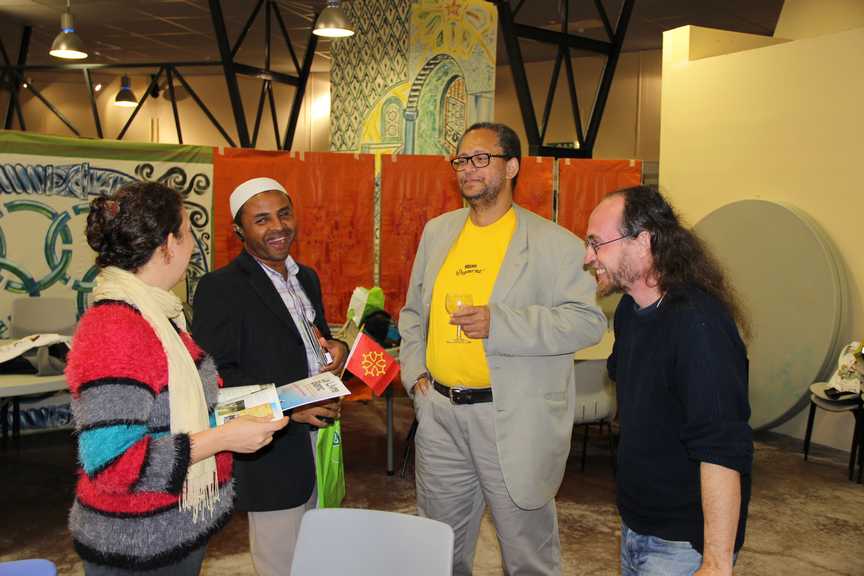 Groupe de quatre personnes discutant dans une salle décorée, lors d’un événement convivial.