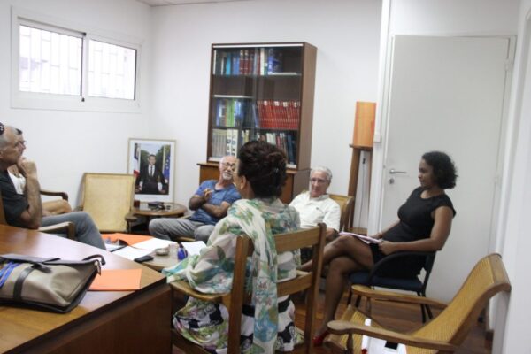 éunion informelle de membres du CCEE dans une salle de travail, avec des documents posés sur une table et des étagères en arrière-plan.