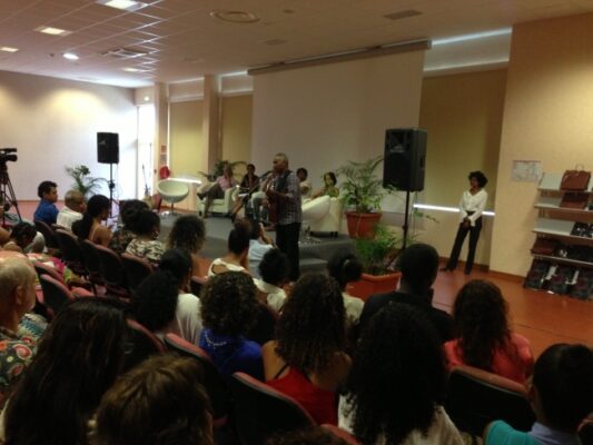 Vue d’ensemble de la salle pendant la remise des prix LanKRéol 2013. Des intervenants se trouvent sur scène devant un écran blanc, tandis que le public est attentif. Une plante décorative et une enceinte sont visibles sur le côté de la scène