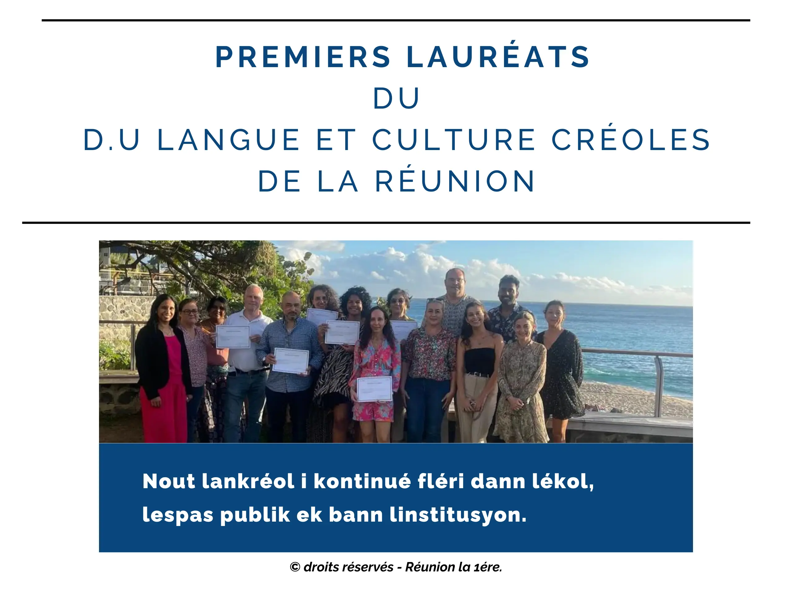 Un groupe de 13 personnes est debout en plein air près de la mer, sous un ciel bleu avec quelques nuages. Ils tiennent des diplômes et sourient pour la photo. Il y a des arbres et une balustrade en pierre à gauche, une rambarde en métal à droite, et un paysage de plage en arrière-plan. Les personnes sont habillées de manière décontractée et colorée.