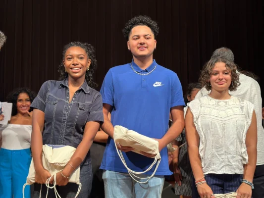 Trois lauréats du concours Kozarlor posant ensemble avec des sacs en main, exprimant leur joie.