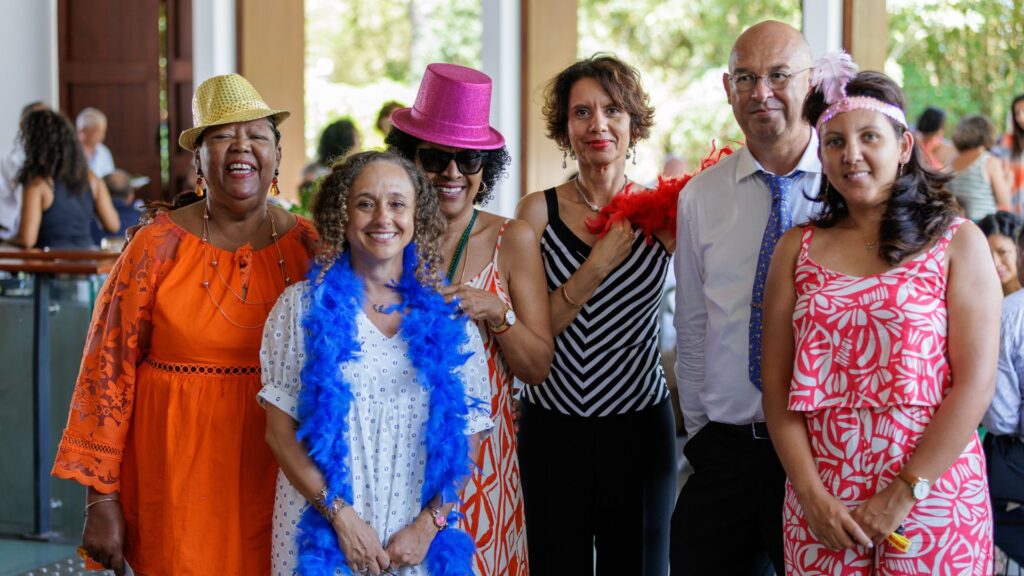 Groupe d'invités portant des accessoires comme un chapeau doré, un chapeau rose brillant et un boa bleu lors des célébrations des 40 ans du CCEE, avec une atmosphère festive et chaleureuse.
