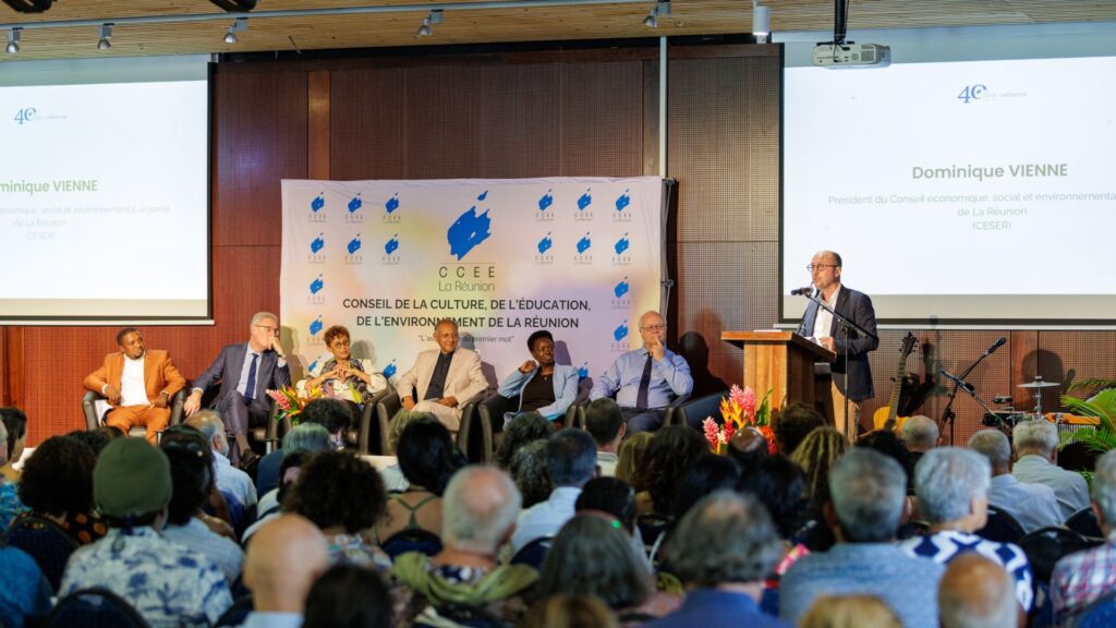 Photo de Dominique Vienne, en costume sombre, s'exprimant au micro derrière un pupitre en bois lors des 40 ans du CCEE. En arrière-plan, des personnalités assises, dont David André, Marie-Jo Lo Thong, Roger Ramchetty, Patricia Profil et Ali Madi