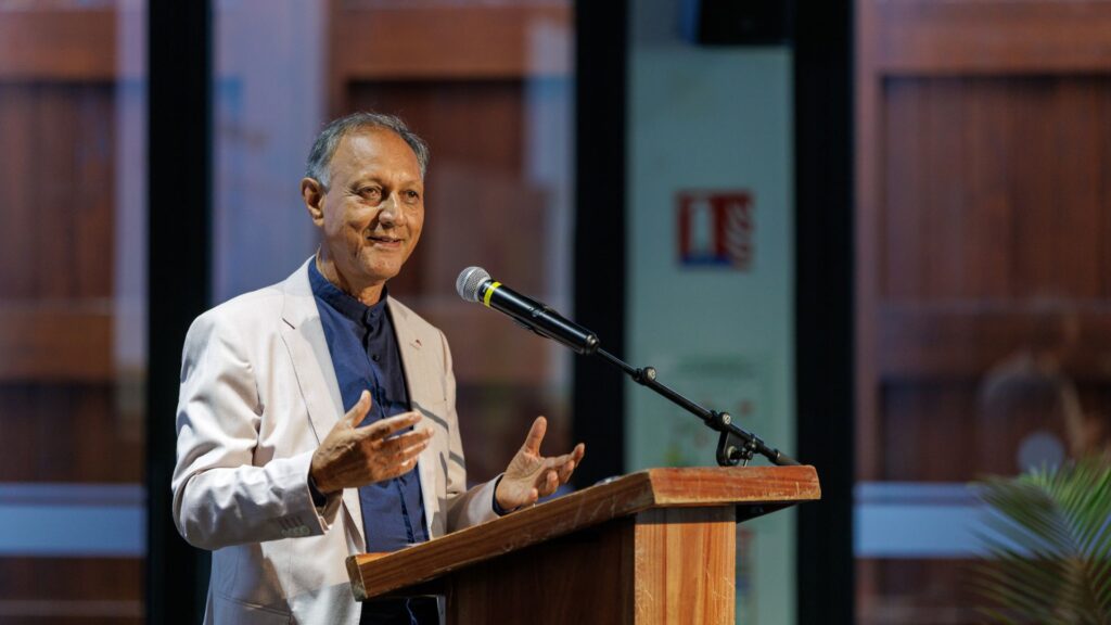 Roger Ramchetty, portant une veste claire et une chemise bleu marine, s'exprimant au micro depuis un pupitre en bois lors de l'événement des 40 ans du CCEE.