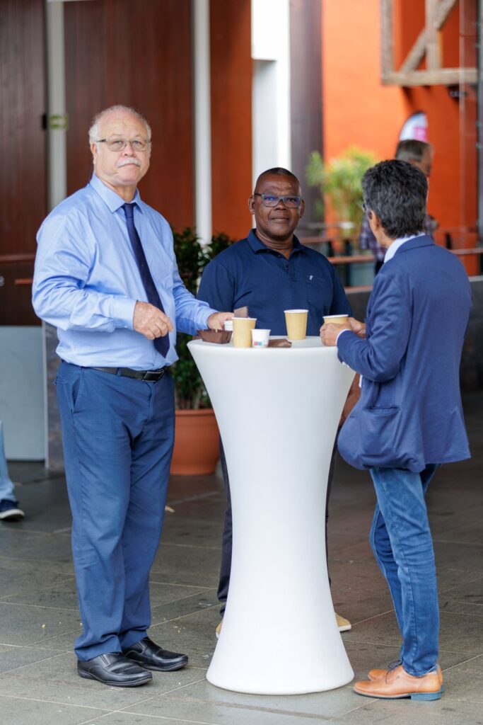 Discussion conviviale entre participants autour d'un café, lors des 40 ans du CCEE, devant un décor coloré et végétalisé