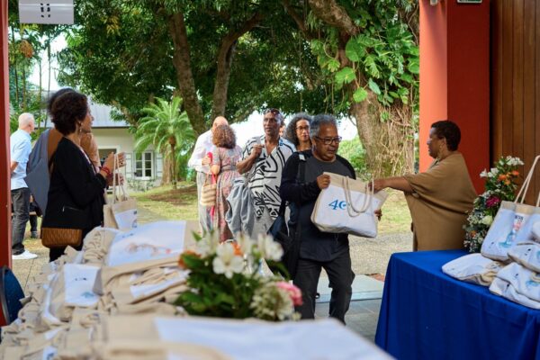 Roger Ramchetty, président du CCEE, vêtu d'une chemise blanche et d'un gilet bleu à motifs fleuris, se tient debout lors des Vintan du Prix Honoré. En arrière-plan, des convives discutent autour des tables dans une ambiance conviviale."