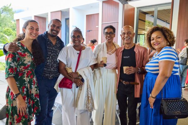 Photo de groupe lors des Vintan du Prix Honoré. Six personnes posent côte à côte en souriant. Une femme porte une robe à motifs floraux rouges, un homme est vêtu d'une veste bleue à motifs, une femme en tenue blanche porte un sac rouge, et une autre en chemise blanche avec un pantalon blanc. Un homme porte une chemise rose ouverte sur un t-shirt noir, et une femme en robe bleue rayée de blanc tient un sac noir."