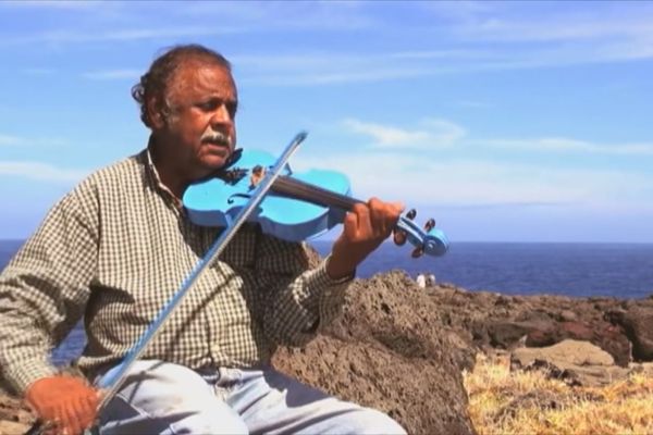 Fred Espel joue du violon bleu au bord de l’océan Indien