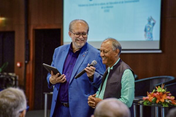Roger Ramchetty et Dominique Picardo échangent au micro pendant une conférence, l’un tient une tablette.