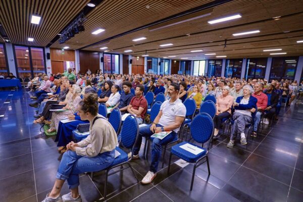 Vue latérale d’un public attentif dans une salle de conférence moderne.